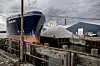 Billedet er taget fra den ene side af havnen med et kig til den anden side, hvor et stort fragtskib er klar til at blive læsset med sten.