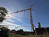 Billedet viser en gul kran på en byggeplads. Foran kranen ses et hegn.